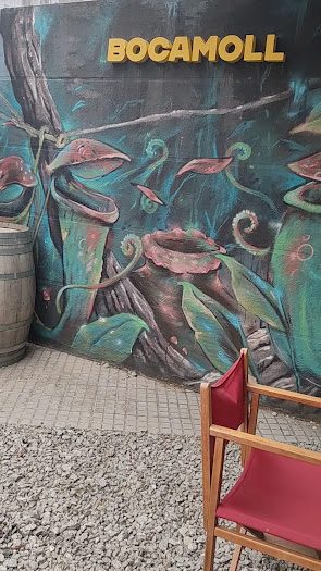 Mural pintado de la terraza con el rótulo dorado del Bar Bocamoll y una barrica de madera
